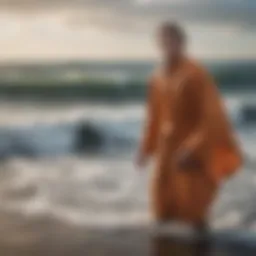 A surfer wrapped in a dry robe against the backdrop of crashing cold waves.