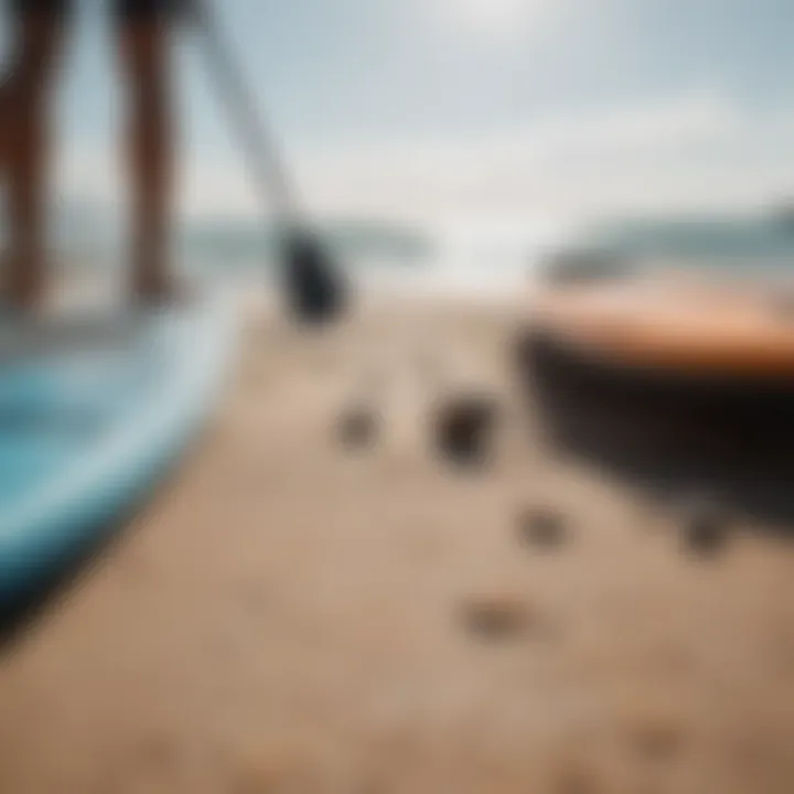 A close-up view of essential paddleboarding gear laid out on a sandy beach.