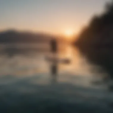 A tranquil scene of a paddleboarder gliding over calm waters during sunset.