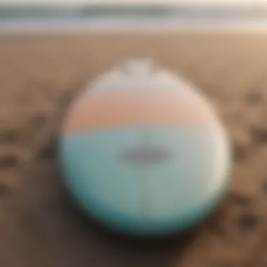 A close-up of a surfboard resting on the sandy shore with gentle waves in the background.